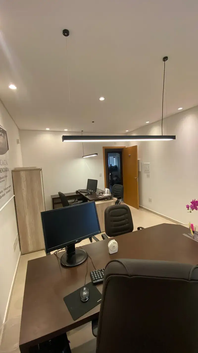 Escritório moderno com luminárias lineares suspensas pretas sobre as secretárias
