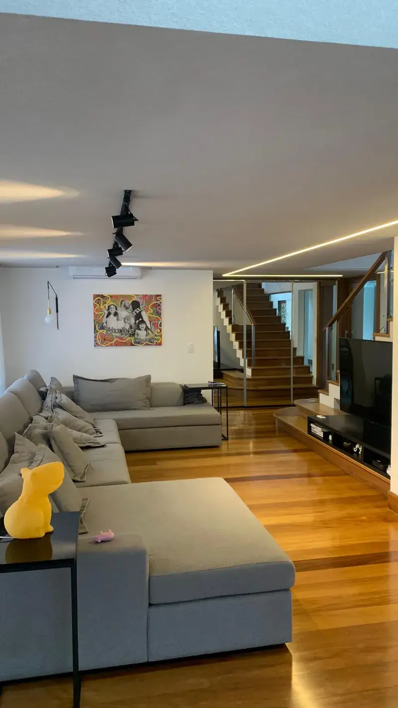 Sala de estar com focos em calha preta e rasgo de luz LED linear no teto