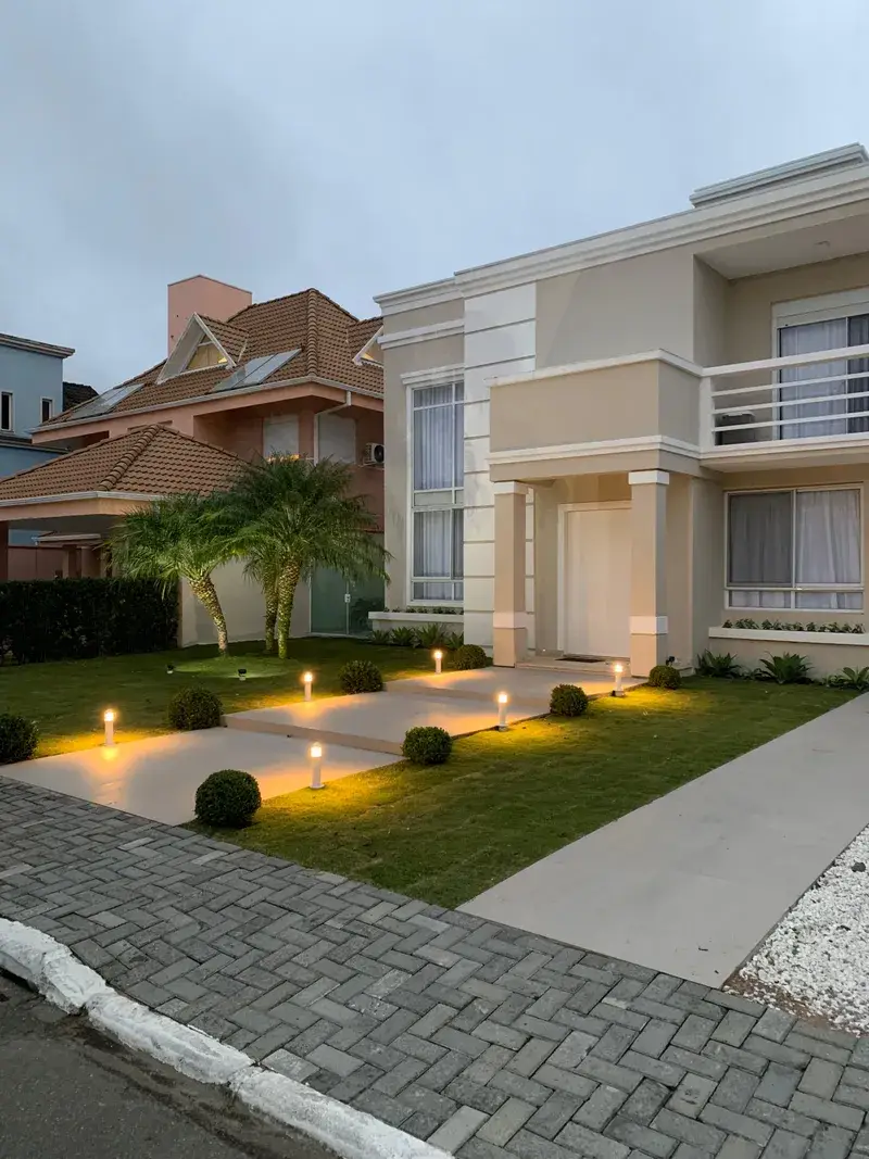 Fachada de vivenda com iluminação de jardim através de balizadores de luz quente