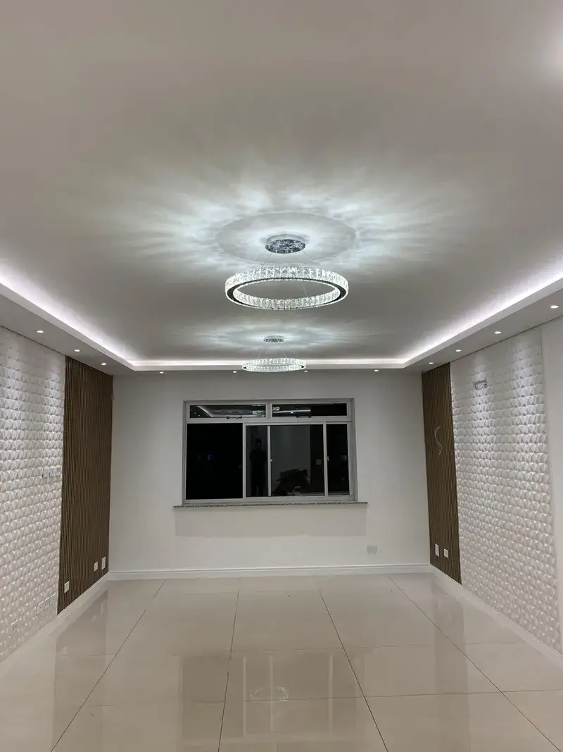 Sala ampla com lustres circulares de cristal e iluminação embutida em sanca